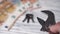 A man`s hand sets up an adjustable spanner on a background of euro banknotes and keys on a white wooden table