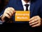 Man`s hand showing orange business card with phrase Emerging Markets - closeup shot on grey background