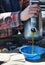 Man`s hand slowly and carefully pouring oil into a vehicle engine.