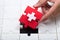 Man`s hand solving jigsaw puzzle with red piece