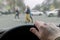 A man`s hand on the steering wheel of a car while braking at a pedestrian crossing