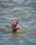 Man`s hand sticks out from the water in the middle of the ocean