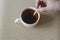 A man`s hand is stirring black tea in a mug with a metal spoon