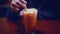 Man`s hand stirs traditional Thai Ice Tea in a glass with a straw