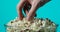 Man`s hand is taking tasty fresh popcorn from transparent glass bowl on blue background.