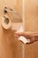 man\'s hand tears off a piece of toilet paper in the toilet