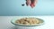 Man`s hand throw a fruits and almonds and berries to bowl with corn rings