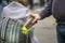 A man`s hand throws a paper coffee cup into a street trash can, close-up, selective focus. Concept: eco-friendly packaging and pac