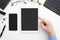 Man`s hand touches a tablet on work desk with smartphone and keyboard on white background. Top view. App and responsive