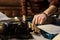 man`s hand typing on vintage typewriter on a piece of newspaper and dark blue velvet fabric on the floor in a dark room with ligh