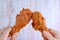 Man`s Hand and Woman`s Hand Clinking Crispy Fried Chicken Drumsticks Against Wooden Wall