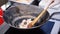 Man`s hand with wooden turner fried chicken meat in large deep pan. Clip. Preparing paella or jambalaya. Nature