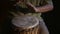 Man`s hands drumming out a beat on an African skin-covered hand drum.