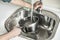 Man\'s hands filling a stainless steel saucepan with running water until it boils