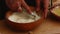 - man's hands grind flour into a bowl with a mortar