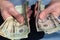 Man`s hands holding out piles of cash in American five and twenty dollar bills