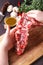 Man`s hands holding rack of the lamb in a process of cooking on a kitchen table
