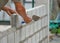 Man`s hands  of industrial bricklayer with  aluminium brick trowel installing brick blocks on construction site