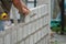 Man`s hands  of industrial bricklayer with  aluminium brick trowel installing brick blocks on construction site