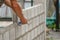 Man`s hands  of industrial bricklayer with  aluminium brick trowel installing brick blocks on construction site, selective focus a