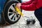 Man\'s hands inflating car wheel using automobile compressor with manometer.