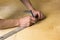Man`s hands marking measurement on plywood board with a pencil and ruler