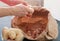 Man`s hands peeling potatoes. Paper bag with cleaning of the potatoes. Potatoes in bowl