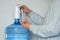 Man& x27;s hands pour water into glass from an automatic water cooler, closeup view.