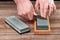 Man`s hands sharpening a pocket knife with a whetstone on a wooden table