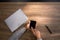 Man`s hands typing cell phone on wooden table background with black pen.