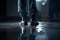 Man\\\'s legs in black leather shoes standing on the floor in the dark