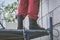 The man`s legs of a builder in rubber boots stand on the scaffolding. Outdoor construction work, pastel shading