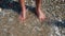 Man`s legs on rocky beach. Concept. Close-up of man standing on Bank and wetting feet. Feet stand on shore pebbles with