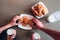 Man`s and woman`s hands are reaching cookies on plate. Also they hold glasses of milk. Isolated on brown background.