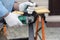 A man in the safety gloves is cutting metal using a green angle grinder tool with sparks on a work bench. Horizontal