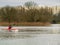 Man in safety vest roving in canoe.