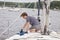 Man on sailboat tying a rope to cleat