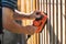 Man sanding wooden fence with electric sander