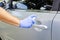 Man sanitizing door handle of his car outdoors.  Male hand in protective glove holding sanitizer closeup