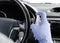 Man sanitizing wheel and salon of his car.  Male hand in protective glove holding sanitizer closeup