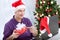 Man with santa cap talking with friend and holding gift