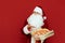 Man in a Santa Claus costume stands on a red background with a pizza box in hand and demonstrates. Positive Santa is pointing her