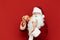 Man in a Santa costume eats a pizza. Pizza for Christmas . Handsome Santa with a slice of pizza in her hand stands on a red