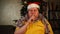 Man in Santa hat and tinsel making silence gesture