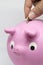 Man saving money in ceramic piggy bank or mud with pink piggy shape
