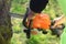 A man is sawing a garden tree with an electric chainsaw.