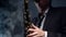 Man saxophonist in a hat and suit plays the saxophone in a smoky studio. Adult male musician blows close-up saxophone