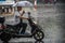 Man on scooter in tropical monsoon rain