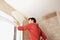 Man Scraping Paint Off Wall In Unrenovated Room