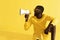 Man screaming in megaphone on yellow background portrait